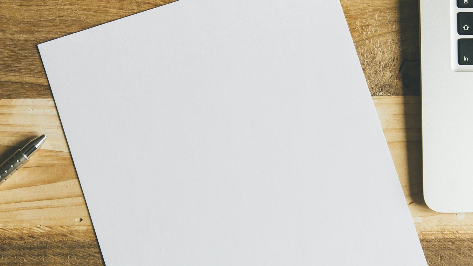 a blank sheet of paper on an oak desk